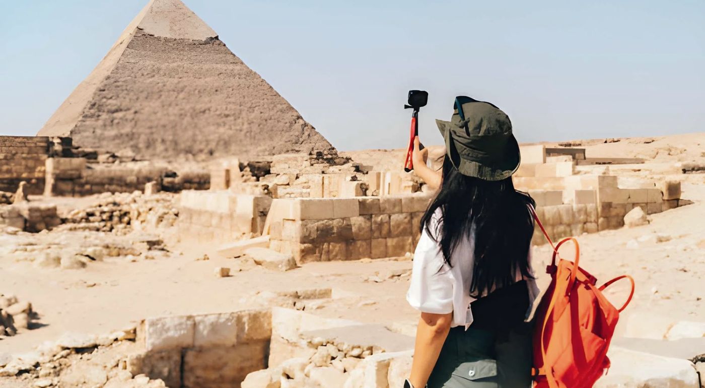 A visitor taking photos at the Giza pyramids